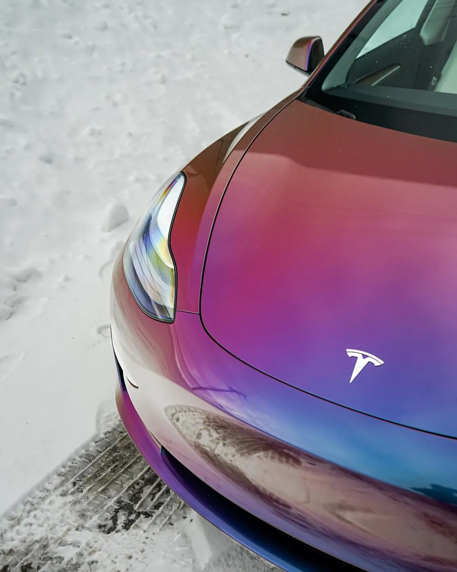 Gros plan sur l’avant d’une Tesla Model 3 habillée d’un vinyle caméléon violet et bleu