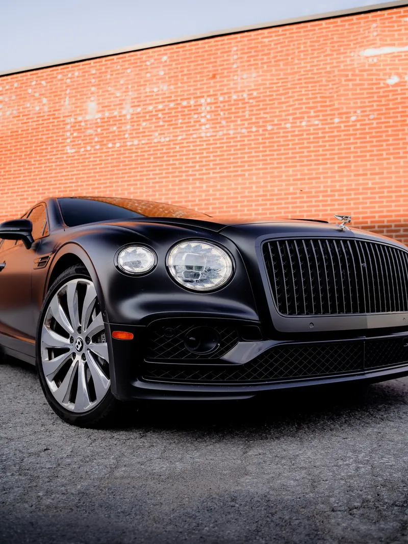 Bentley Flying Spur noire mate devant un mur de brique